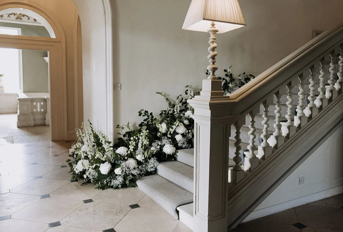 White flowers arranged along a grand interior staircase